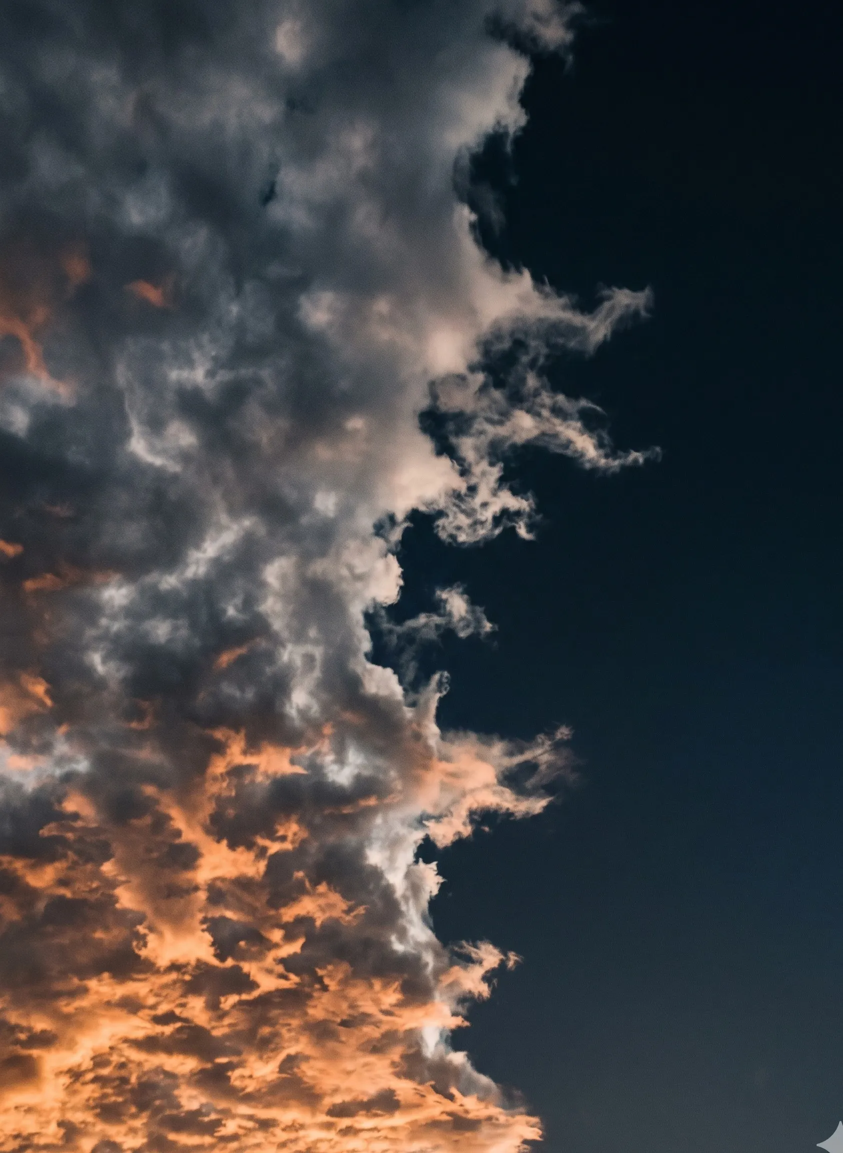 A wall of dense cloud meeting a clear dark sky in a jagged irregular edge, dawn light catching the cloud underside